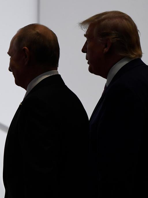 US-Präsident Trump und Russlands Präsident Putin wenden sich gemeinsam zum Gehen, beide sind im Profil und nur im Umriss ihrer Schatten zu erkennen.