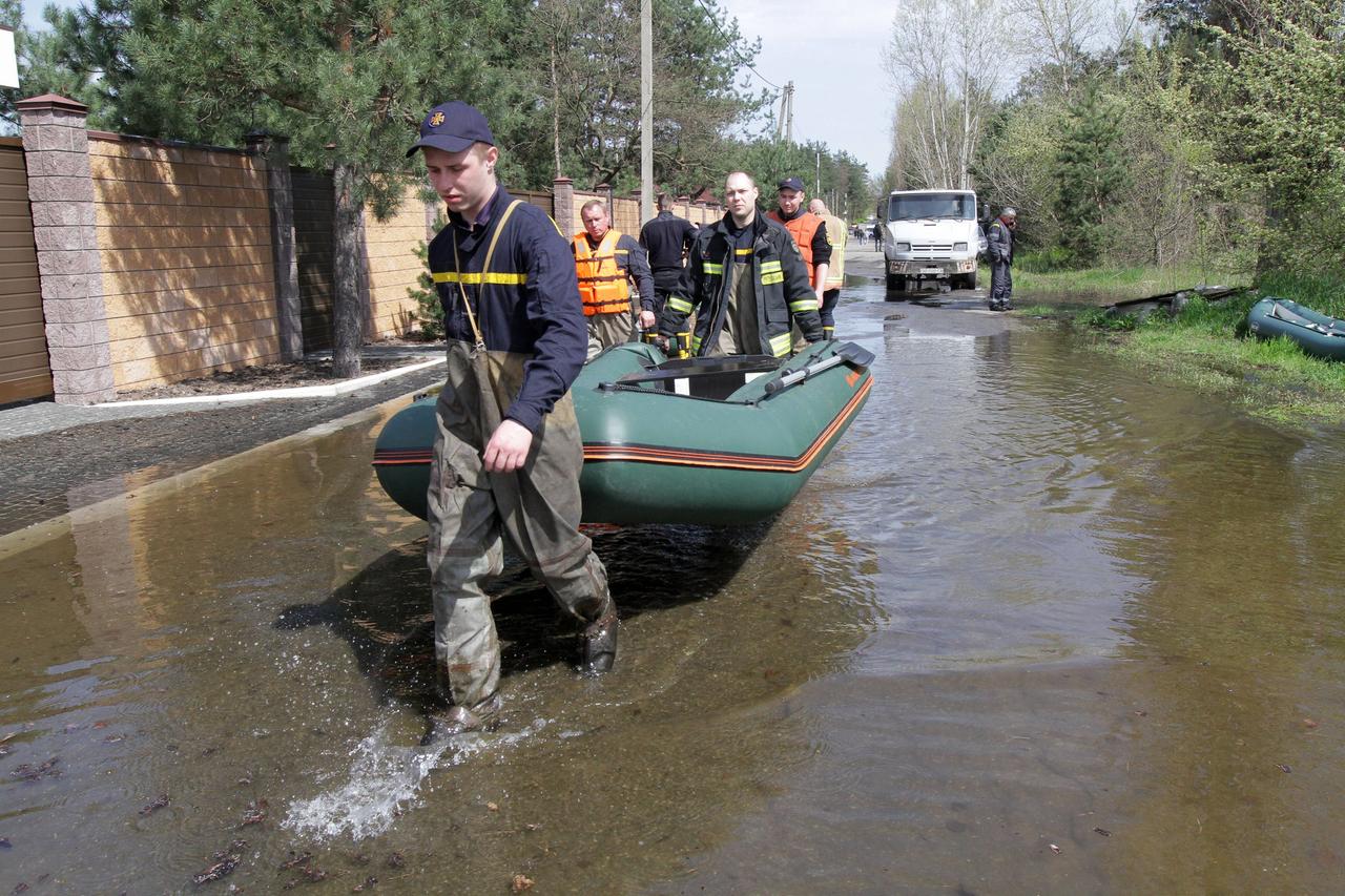 Ulkraine, Obukhivka; Rettungskräfte ziehen ein Schlauchboot auf einer überschwemmten Straße in der Region Dnipropetrowsk. 