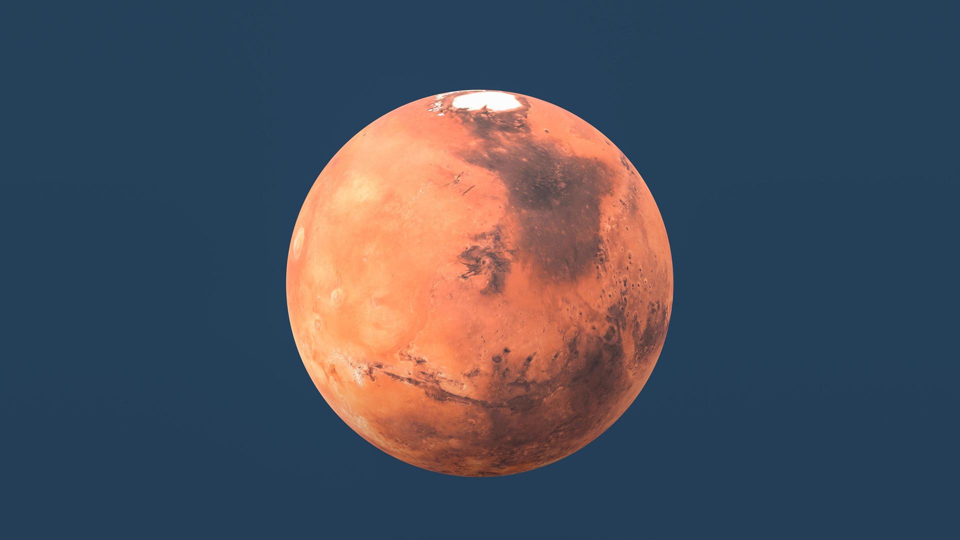 Ein Bild von dem Planeten Mars. Der kugelförmige Mars wirkt rötlich. Der Hintergrund von dem Bild ist dunkelblau.