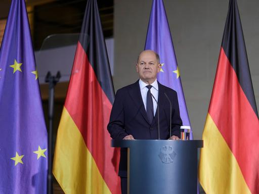 Bundeskanzler Scholz gibt ein Pressestatement vor dem Kanzleramt - er steht vor deutschen und europäischen Flaggen. 