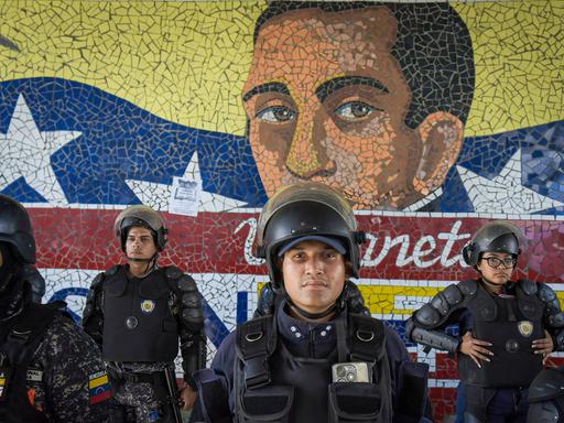 Mitglieder der venezolanischen Polizei patrouillieren am 31. Juli in der venezolanischen Hauptstadt Caracas vor einem Wandbild des Nationalhelden Simón Bolívar.