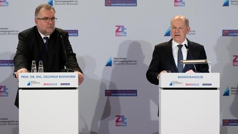 Siegfried Russwurm und Olaf Scholz stehen nebeneinander an zwei Rednerpulten. Scholz sagt gerade etwas. Im Hintergrund eine weiße Wand mit Logos der Messe.