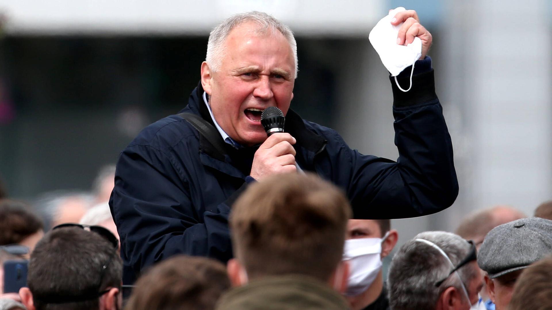 Nikolai Statkevich hält ein Mikrofon und spricht eindringlich zu Menschen, die vor ihm stehen.