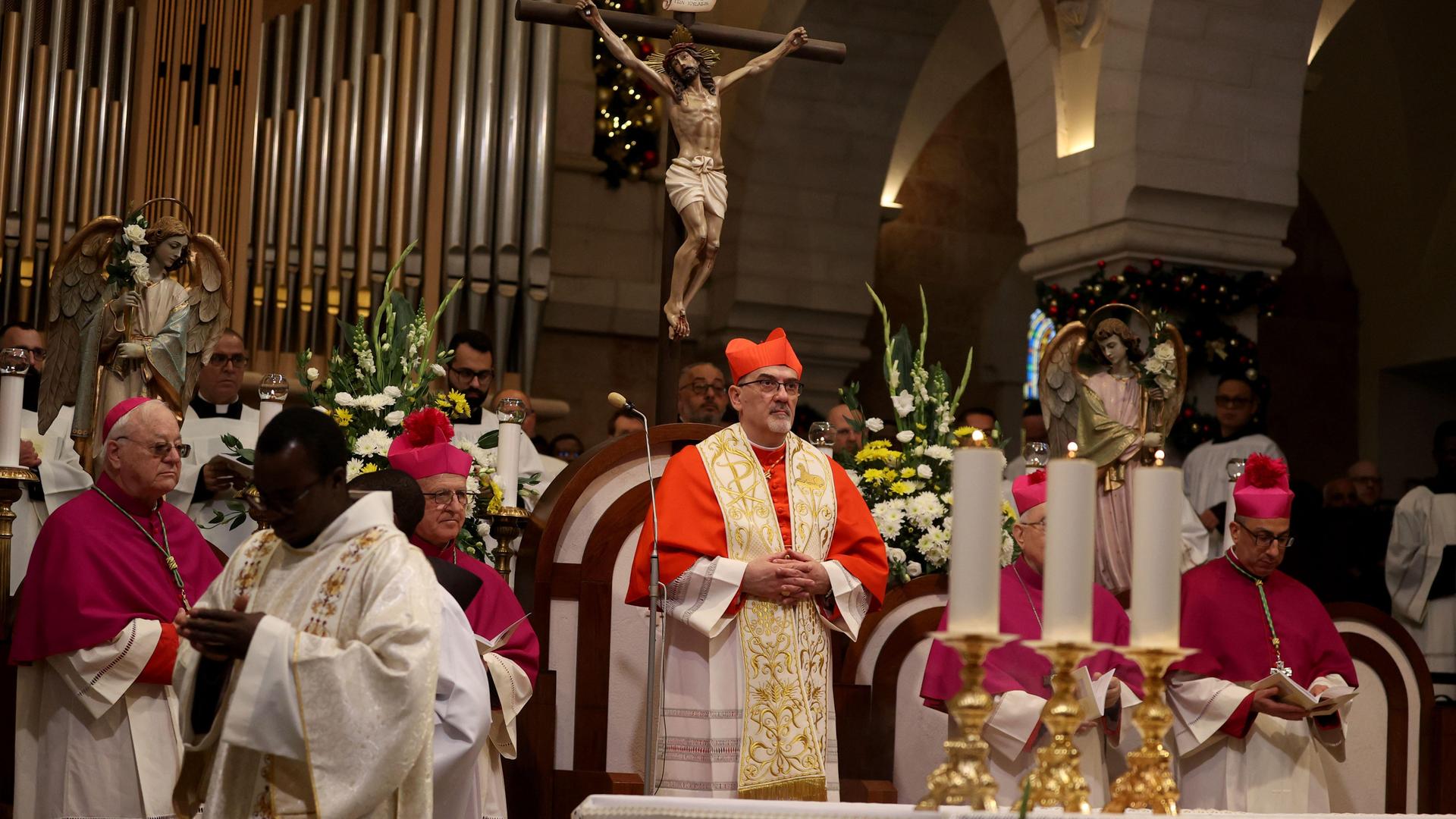 Hinter einem Altar mit drei Kerzen stehen Geistliche und führen durch die Messe
