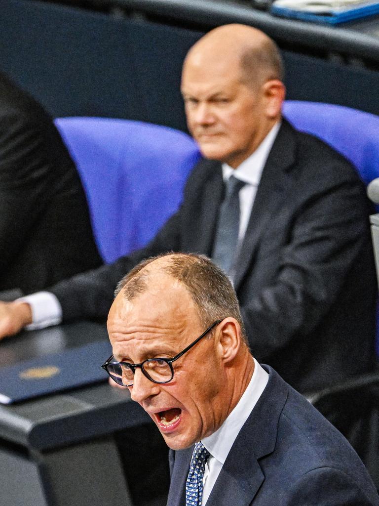 Merz (CDU) am Rednerpult im Bundestag. Dahinter Scholz (SPD) und Habeck (Grüne).