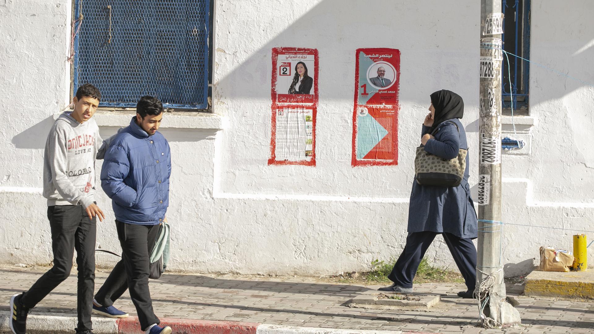 FUßgänger gehen an Wahlplakaten in Tunis vorbi. 