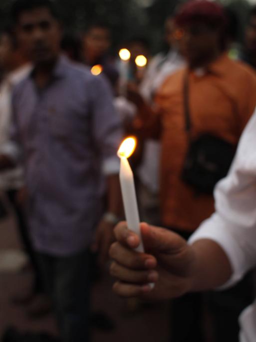 Ein Mann hält eine brennende weiße Kerze in der Hand, aufgenommen am 28.11.2016 bei einer Gedenkfeier für den kubanischen Revolutionsführer Fidel Castro in Dhaka, Bangladesch