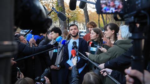 Der Sprecher der französischen Studentenvereinigung USL, Ryad Rani steht in einer Gruppe. Er wird von Journalisten befragt.