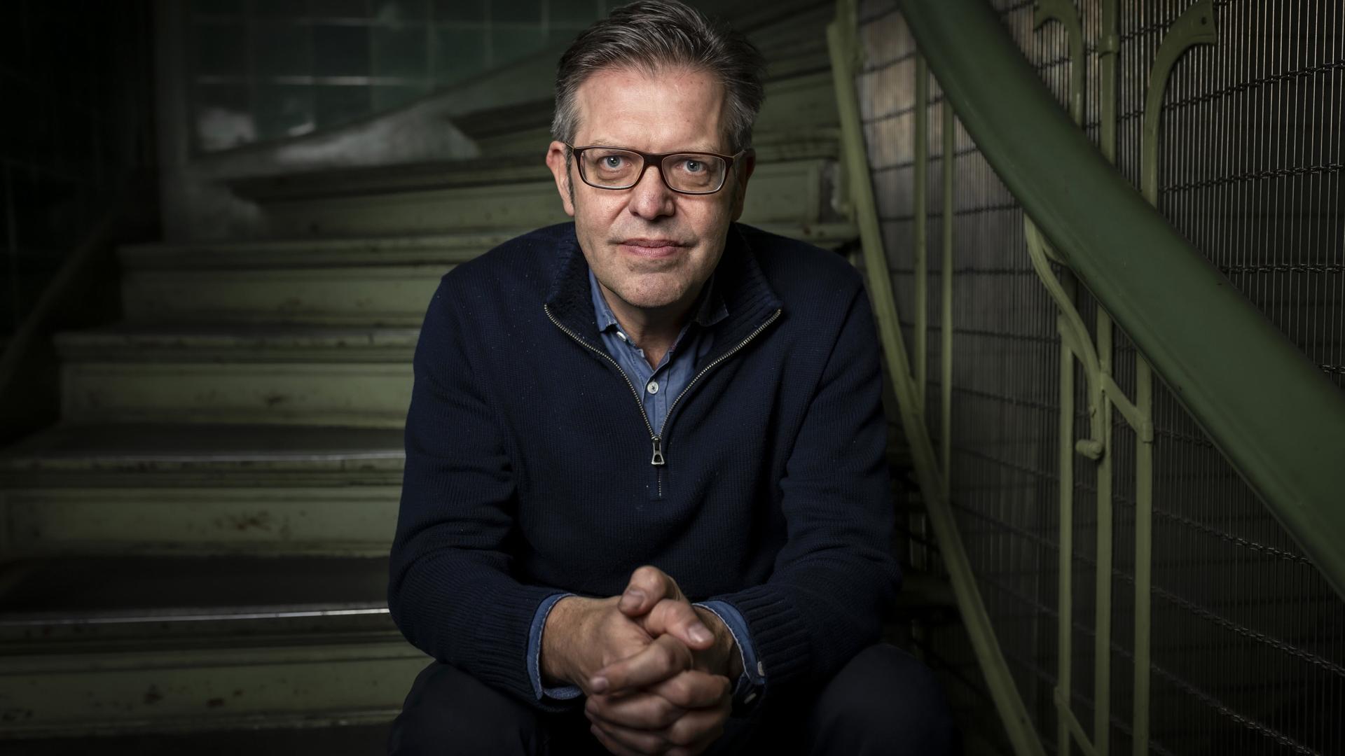 Portraitbild von Steffen Mau, der auf einer Treppe sitzt.