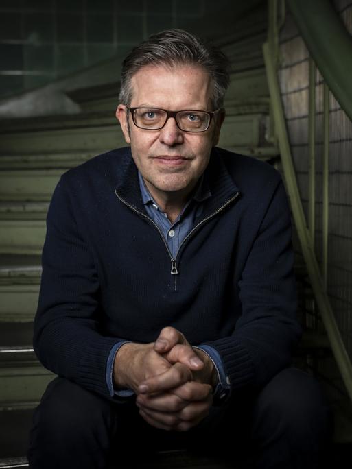 Porträt des Soziologen Steffen Mau, der auf einer Treppe sitzt.