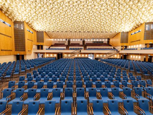Der renovierte große Konzertsaal der Beethovenhalle in Bonn mit blauen Sitzen und Deckenbeleuchtung.  