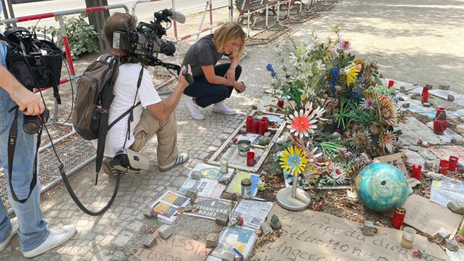Bild aus der ARD-Reportage von Jessy Wellmer "Russland, Putin und wir Ostdeutsche", darauf ist die Reporterin zu sehen, wie sie an einem Gedenkort für die Opfer des Ukraine-Überfalls durch Russland kniet. Bild aus der ARD-Reportage von Jessy Wellmer "Russland, Putin und wir Ostdeutsche", darauf ist die Reporterin zu sehen, wie sie an einem Gedenkort für die Opfer des Ukraine-Überfalls durch Russland kniet.