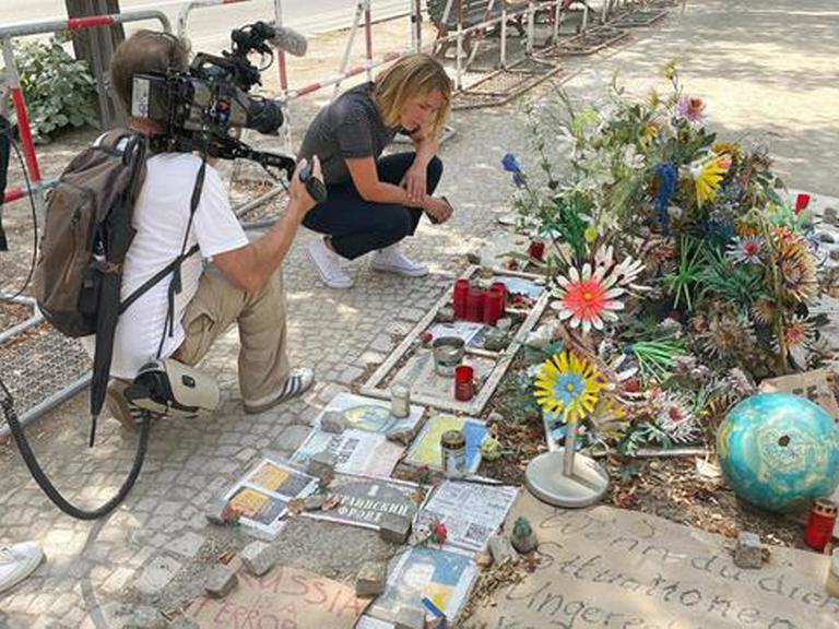 Bild aus der ARD-Reportage von Jessy Wellmer "Russland, Putin und wir Ostdeutsche", darauf ist die Reporterin zu sehen, wie sie an einem Gedenkort für die Opfer des Ukraine-Überfalls durch Russland kniet.