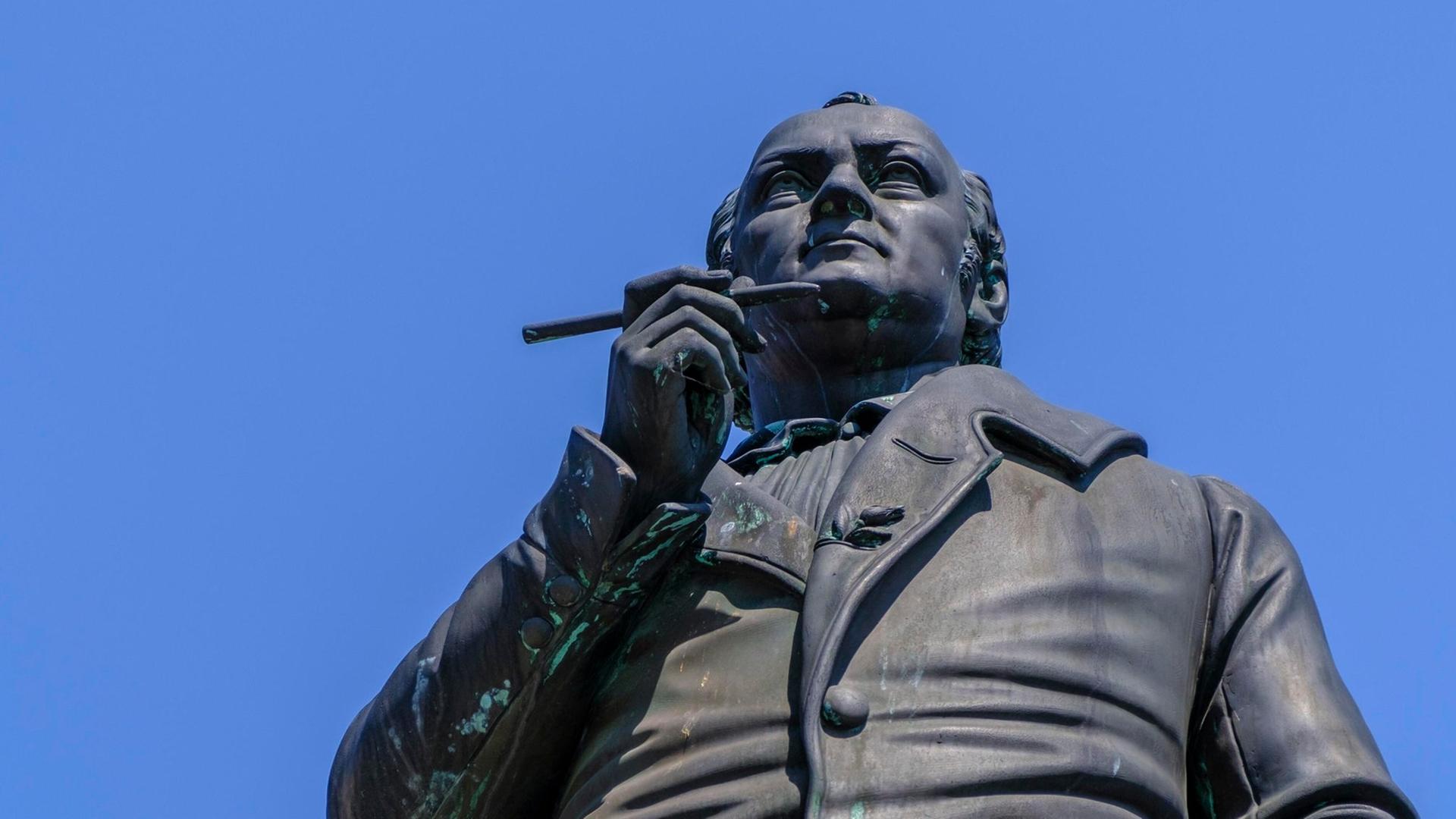 Blick von unten hinauf zum Denkmal des Dichters Jean Paul, der überlegend einen Stift in dier Nähe seiner Lippen hält. Blick von unten hinauf zum Denkmal des Dichters Jean Paul, der überlegend einen Stift in dier Nähe seiner Lippen hält.