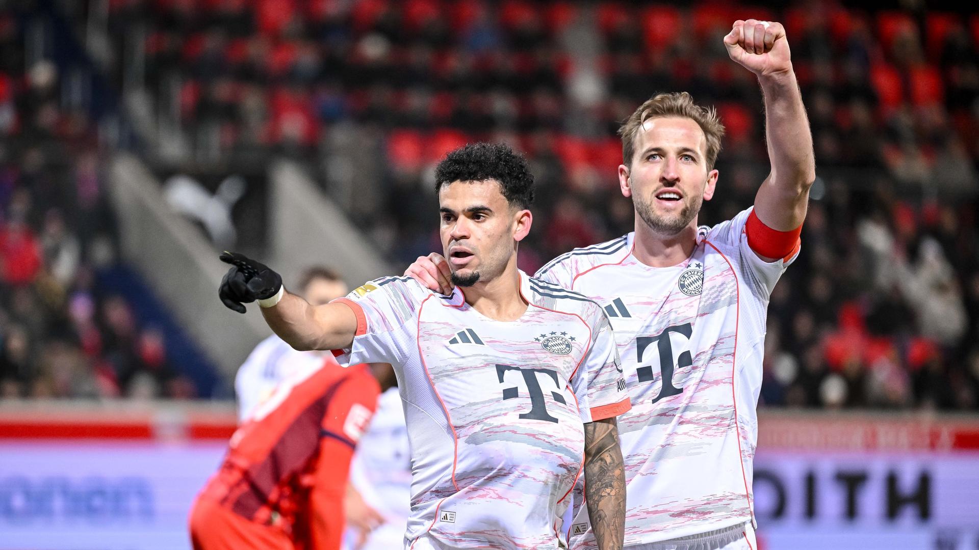 Das Bild zeigt zwei Fußballer, die sich seitlich umarmen und ihre beiden freien Hände zum Torjubel hochrecken.