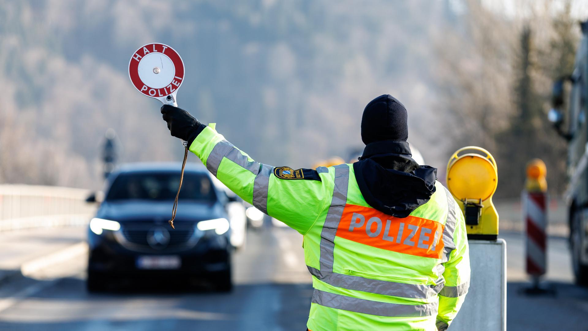 Ein Polizist der Bayerischen Grenzpolizei stoppt am 6. Februar 2025 am Grenzübergang von Österreich nach Deutschland in Oberaudorf (Bayern) ein Auto an einer Kontrollstelle der Polizei. 