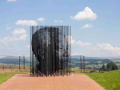Eine große moderne Skulptur, die dem Gesicht von Nelson Mandela nachempfunden ist. Sie steht vor einer weiten Landschaft in Howick, Südafrika.