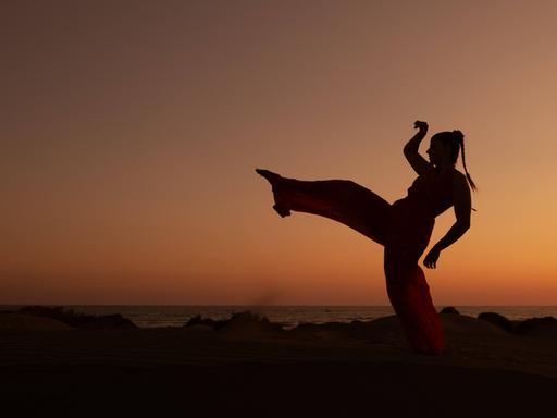 Eine Frau tanzt bei Sonnenuntergang am Strand - undatiertes Foto
