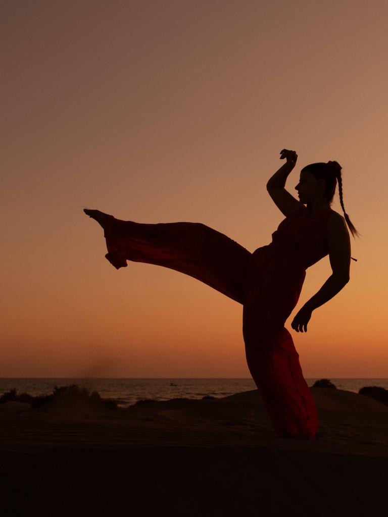 Eine Frau tanzt bei Sonnenuntergang am Strand - undatiertes Foto