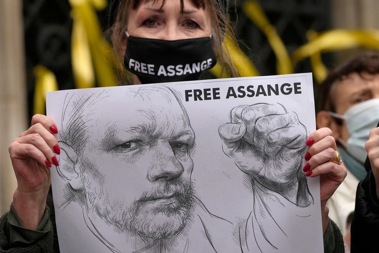 Vor dem High Court in London hält eine Unterstützerin mit Maske ein Plakat hoch. Zu sehen ist eine Bleistift-Zeichnung von Wikileaks-Gründer Julian Assange und die Forderung "FREE ASSANGE".