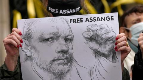 Vor dem High Court in London hält eine Unterstützerin mit Maske ein Plakat hoch. Zu sehen ist eine Bleistift-Zeichnung von Wikileaks-Gründer Julian Assange und die Forderung "FREE ASSANGE".
