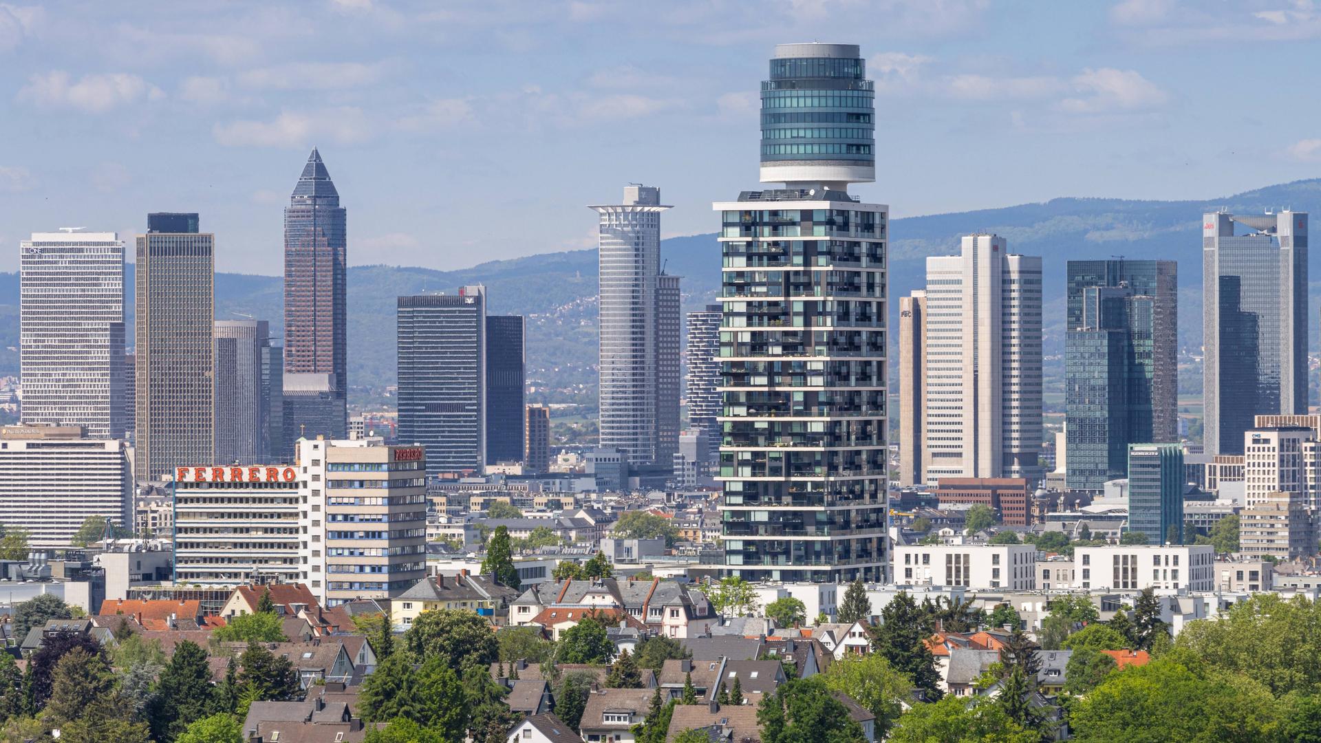 Blick vom Goethetur über den Henninger Turm bis hin zur Frankfurter Skyline. Dazwischen sind kleine Wohnhäuser zu sehen.