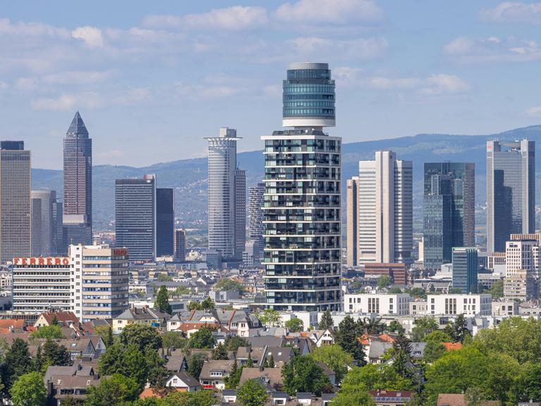 Blick vom Goethetur über den Henninger Turm bis hin zur Frankfurter Skyline. Dazwischen sind kleine Wohnhäuser zu sehen.