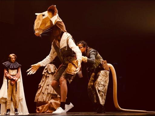 Szene eines Theaterstücks beim europäischen Jugendtheaterfestival „For/with/by“ in Madrid, mehrere Jugendliche spielen eine übergrosse Ratte.
