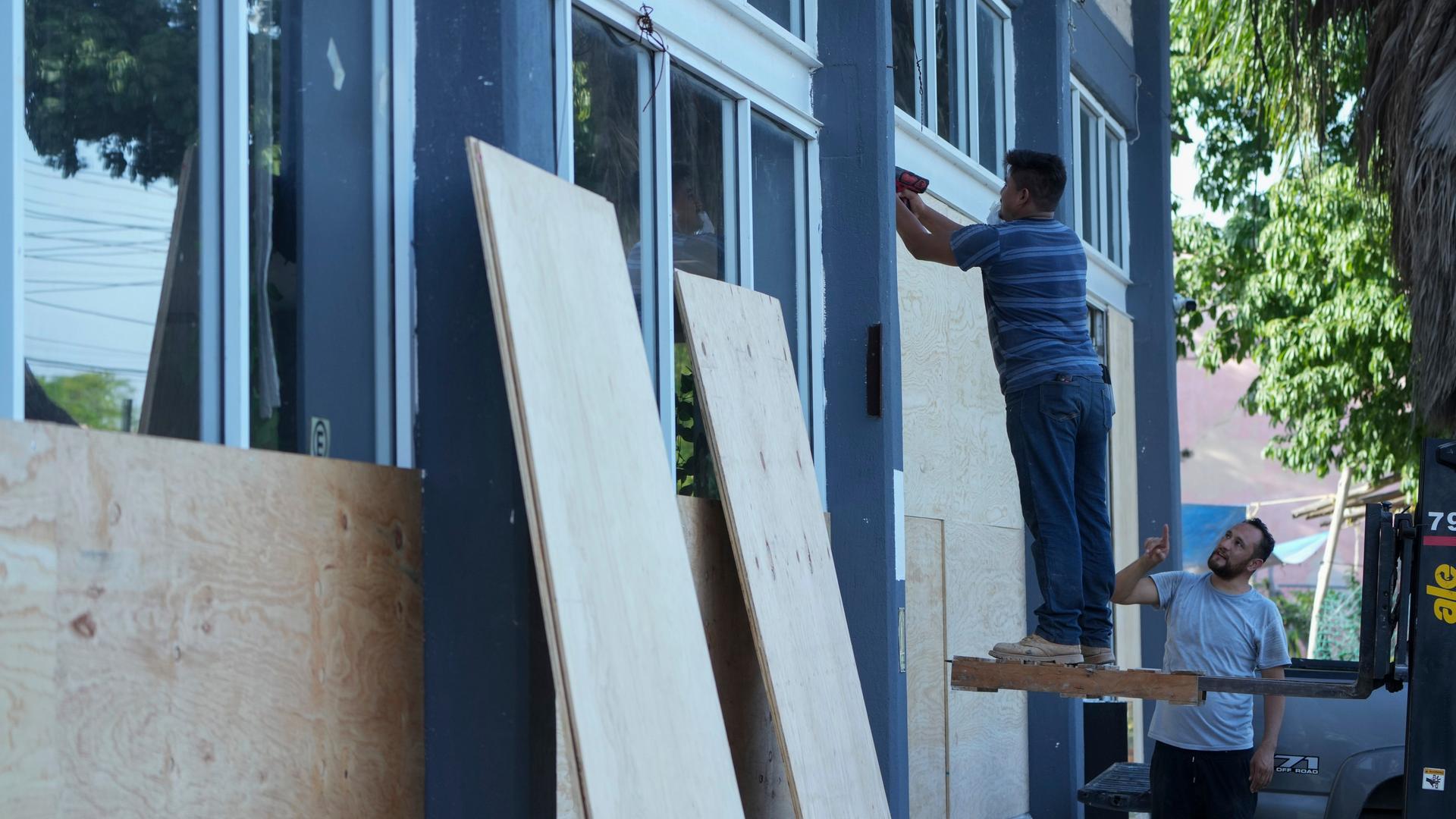 Zwei Männer dichten ein Haus mit Holzplatten ab.