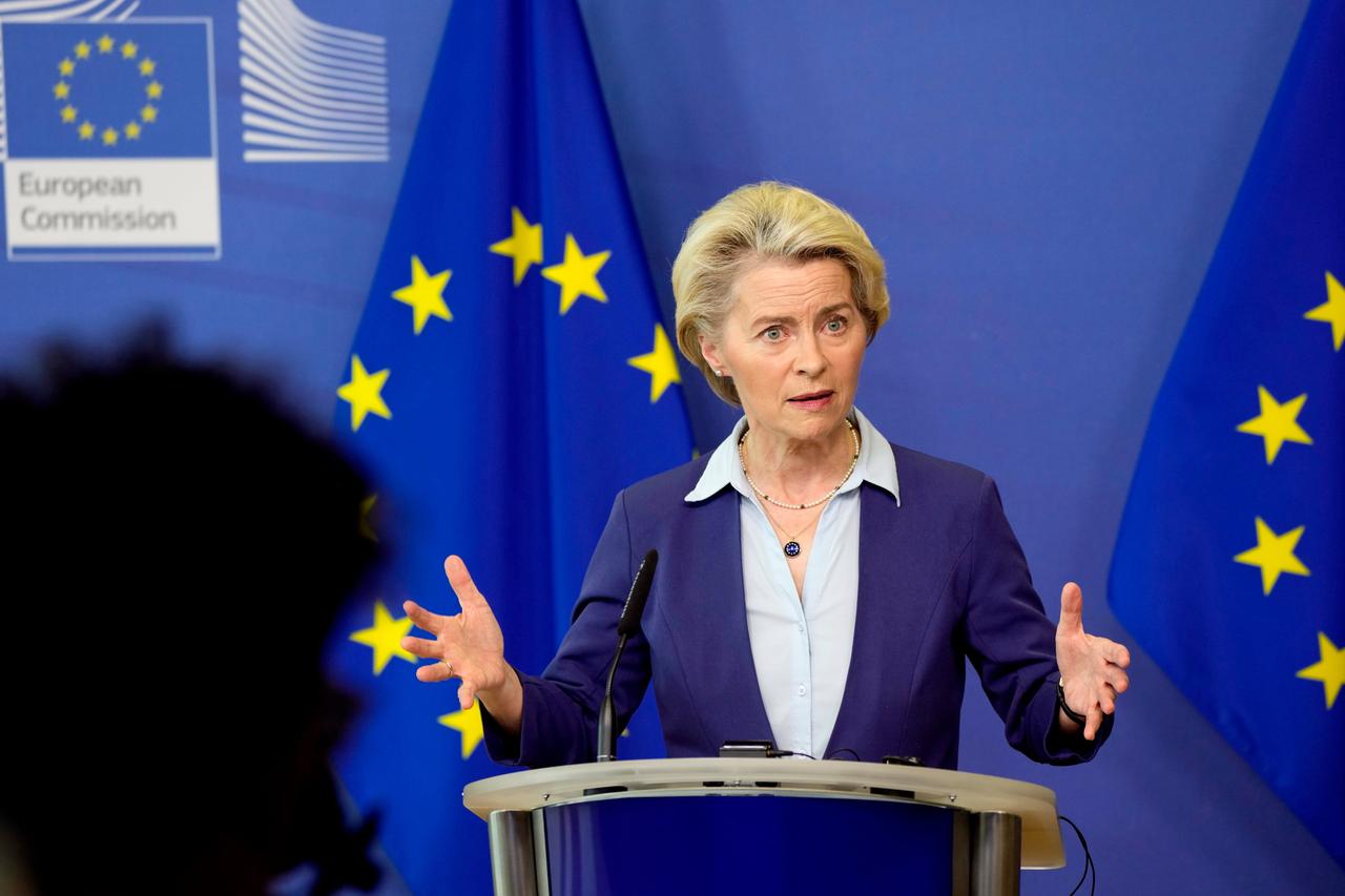 Von der Leyen steht an einem Redepult und gestikuliert mit beiden Händen. Im Hintergrund sieht man zwei Flaggen der Europäischen Union.