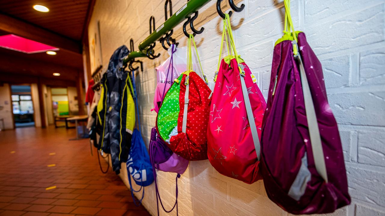 An den Kleiderhaken im Flur einer Grundschule hängen Turnbeutel und Jacken der Schulkinder. 