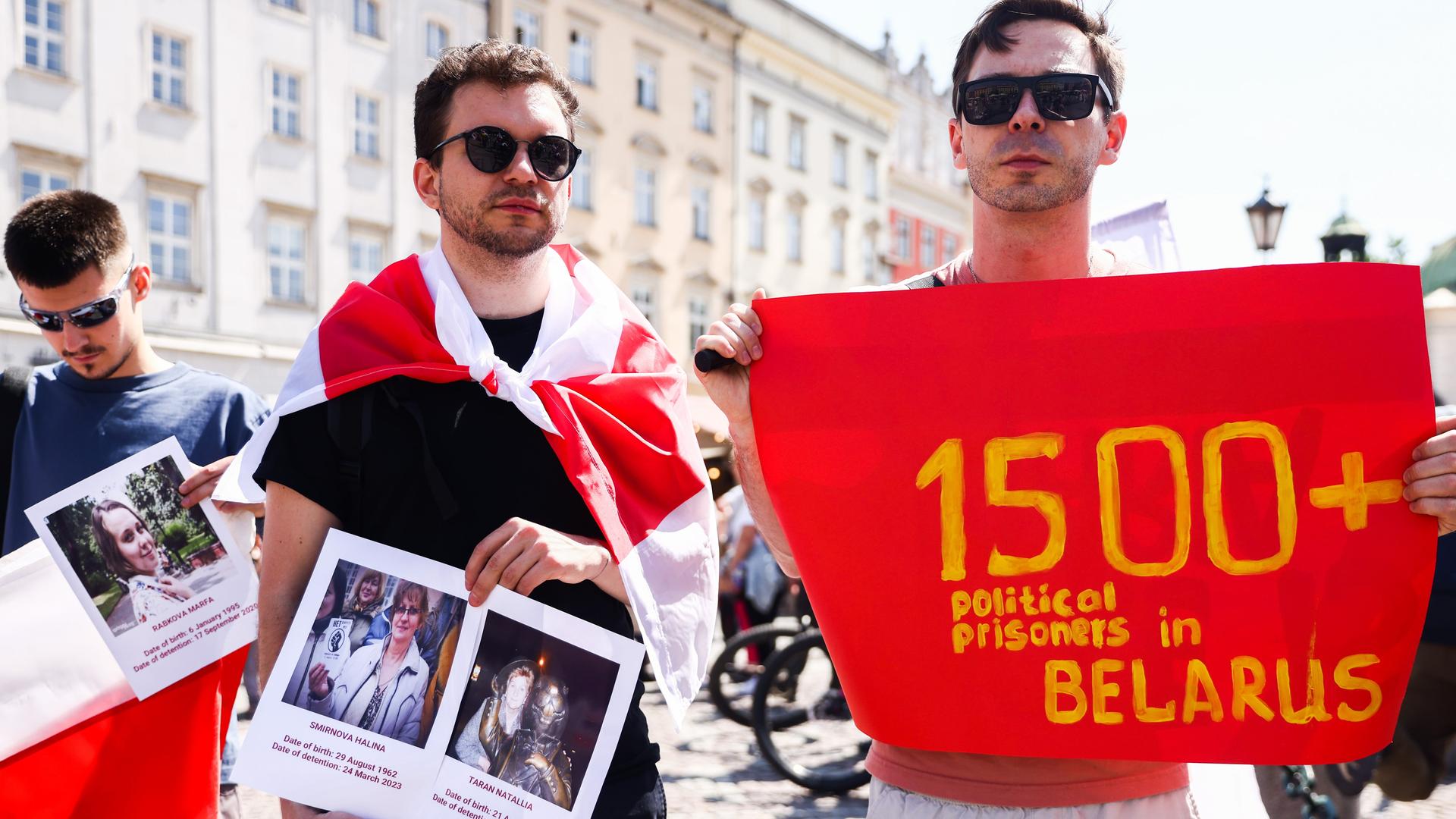 Zwei junge Männer halten Bilder politischer Gefangener und ein Banner, das auf mehr als 1500 politische Gefangene in Belarus verweisen soll.