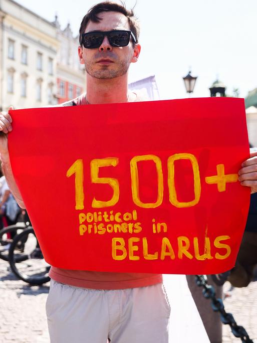 Zwei junge Männer halten Bilder politischer Gefangener und ein Banner, das auf mehr als 1500 politische Gefangene in Belarus verweisen soll.