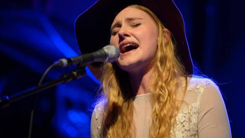 Die Sängerin Mia Diekow hat die Augen geschlossen und singt in in Mikrofon - sie trägt einen schwarzen Cowboy-Hut.