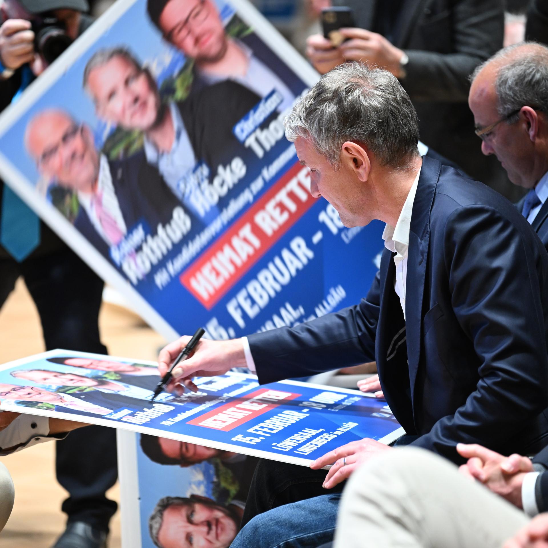 Der thüringische AfD-Vorsitzende Björn Höcke signiert im Löwensaal vor seiner Rede ein paar Wahlplakate für seine Anhänger. 