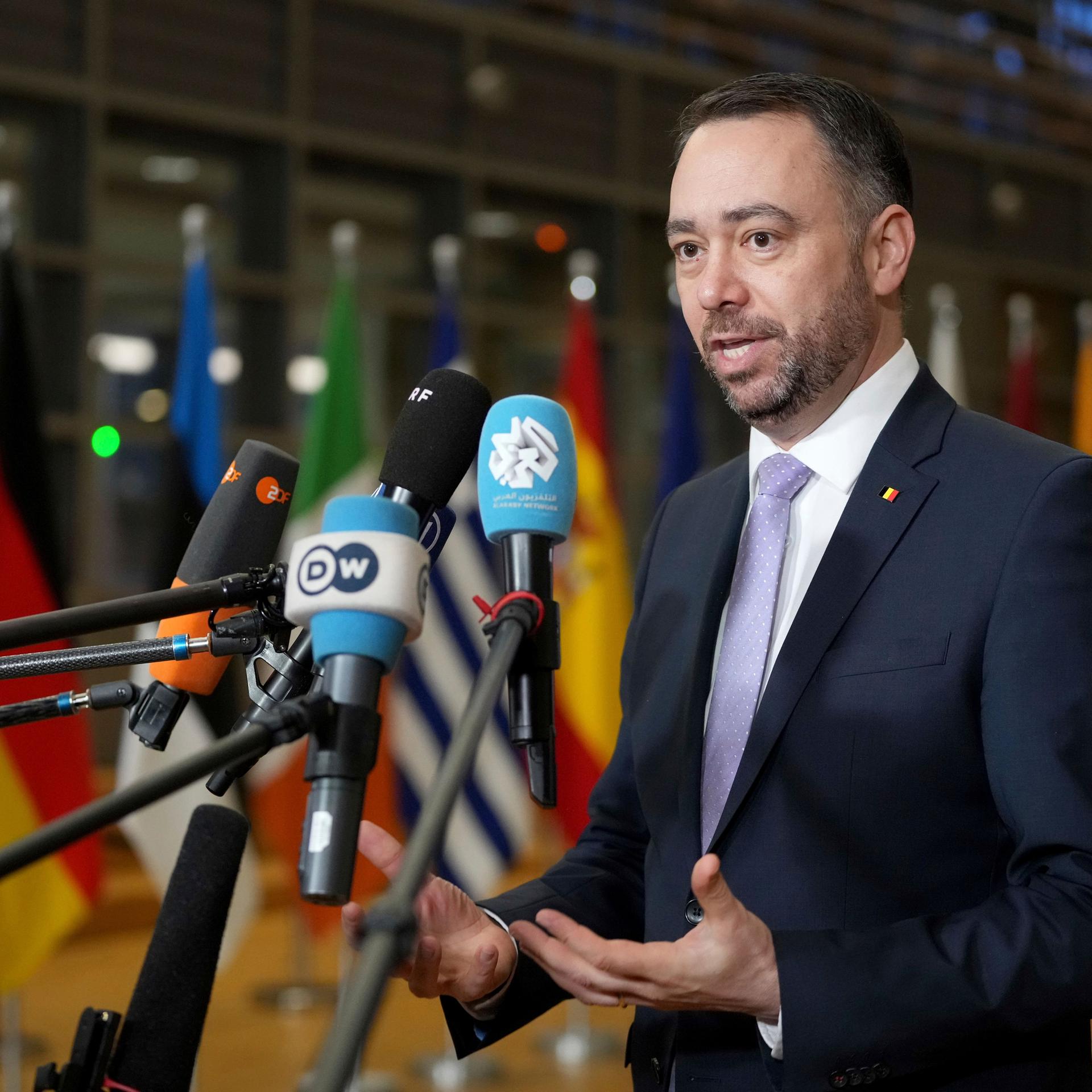 Der belgische Außenminister Prevot steht hinter Mikrofonen und spricht.