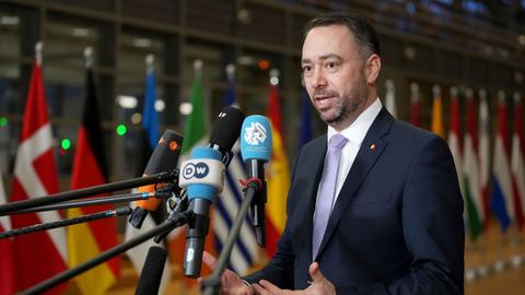 Der belgische Außenminister Prevot steht hinter Mikrofonen und spricht.