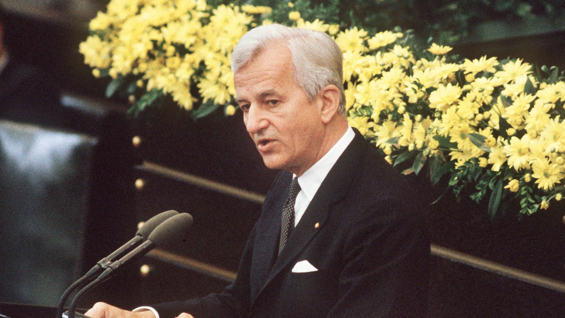 Der deutsche Bundespräsident Richard von Weizsäcker bei seiner vielbeachteten Rede im Bonner Bundestag am 8.5.1985 während der Feierstunde zum Ende des 2. Weltkrieges. Er steht im schwarzen Anzug vor einem gelben Blumenbouquet am Mikrofon. Der deutsche Bundespräsident Richard von Weizsäcker bei seiner vielbeachteten Rede im Bonner Bundestag am 8.5.1985 während der Feierstunde zum Ende des 2. Weltkrieges. Er steht im schwarzen Anzug vor einem gelben Blumenbouquet am Mikrofon.