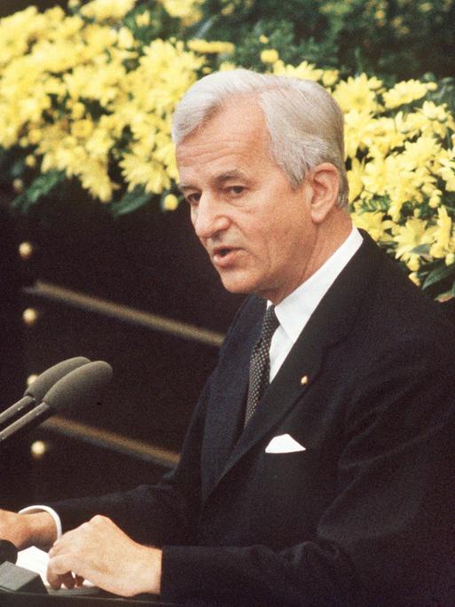 Der deutsche Bundespräsident Richard von Weizsäcker bei seiner vielbeachteten Rede im Bonner Bundestag am 8.5.1985 während der Feierstunde zum Ende des 2. Weltkrieges. Er steht im schwarzen Anzug vor einem gelben Blumenbouquet am Mikrofon. Der deutsche Bundespräsident Richard von Weizsäcker bei seiner vielbeachteten Rede im Bonner Bundestag am 8.5.1985 während der Feierstunde zum Ende des 2. Weltkrieges. Er steht im schwarzen Anzug vor einem gelben Blumenbouquet am Mikrofon.