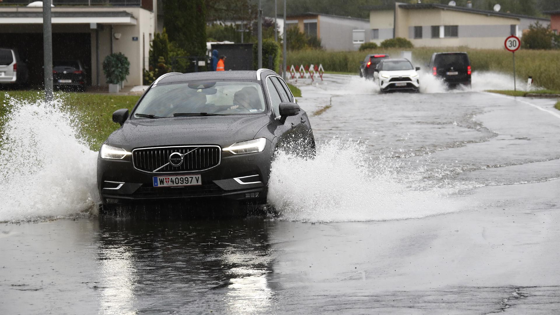 Autos fahren auf einer überfluteten Straße in Viktring bei Klagenfurt in Kärnten. Autos fahren auf einer überfluteten Straße in Viktring bei Klagenfurt in Kärnten.