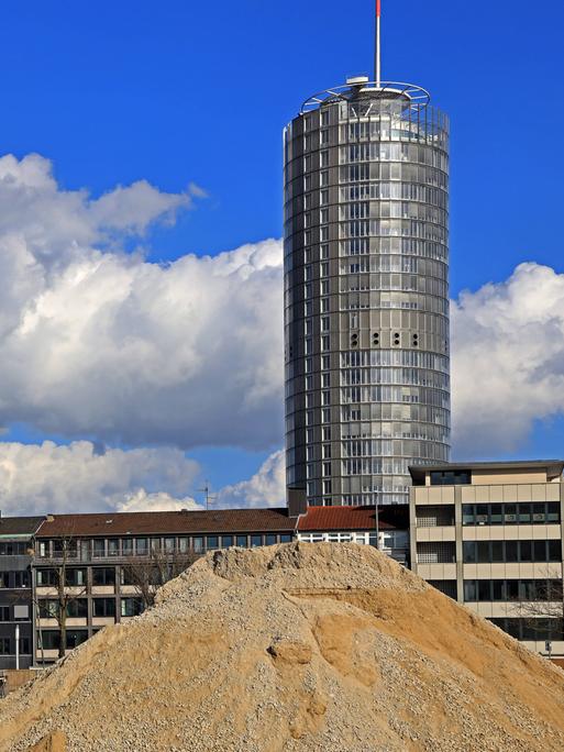 Bauschutt und sandiger Erdaushub vor der Skyline mit RWE-Turm in Essen.