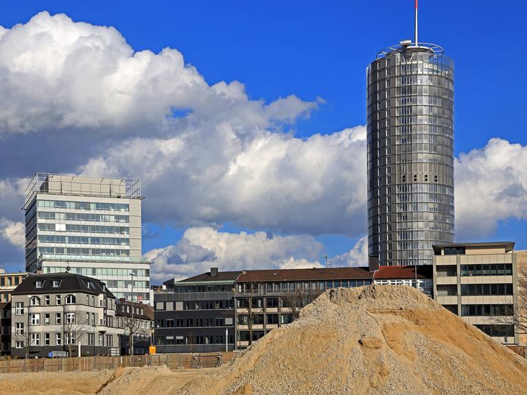 Bauschutt und sandiger Erdaushub vor der Skyline mit RWE-Turm in Essen.