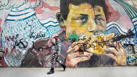 Ein Soldat geht vor einem revolutionären Wandgemälde an einer Mauer der Märtyrer in der Nähe des Tahrir-Platzes in Kairo, Ägypten. Das Gemälde erinnert an die Demonstranten, die während des Aufstandes 2011 auf dem Tahrir-Platz getötet wurden. 
