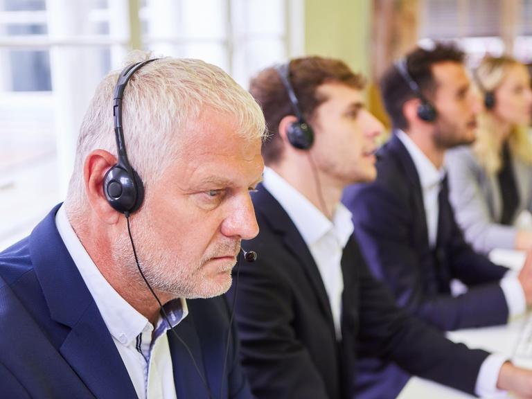 Leute mit Headset bei einer Schulung für Hotline im Callcenter.