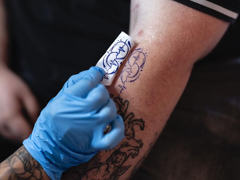 Ein auf einem Oberarm frisch gestochenes Tattoo in Herzschlagform, das für die Organspende sensibilisieren will. Ein auf einem Oberarm frisch gestochenes Tattoo in Herzschlagform, das für die Organspende sensibilisieren will.