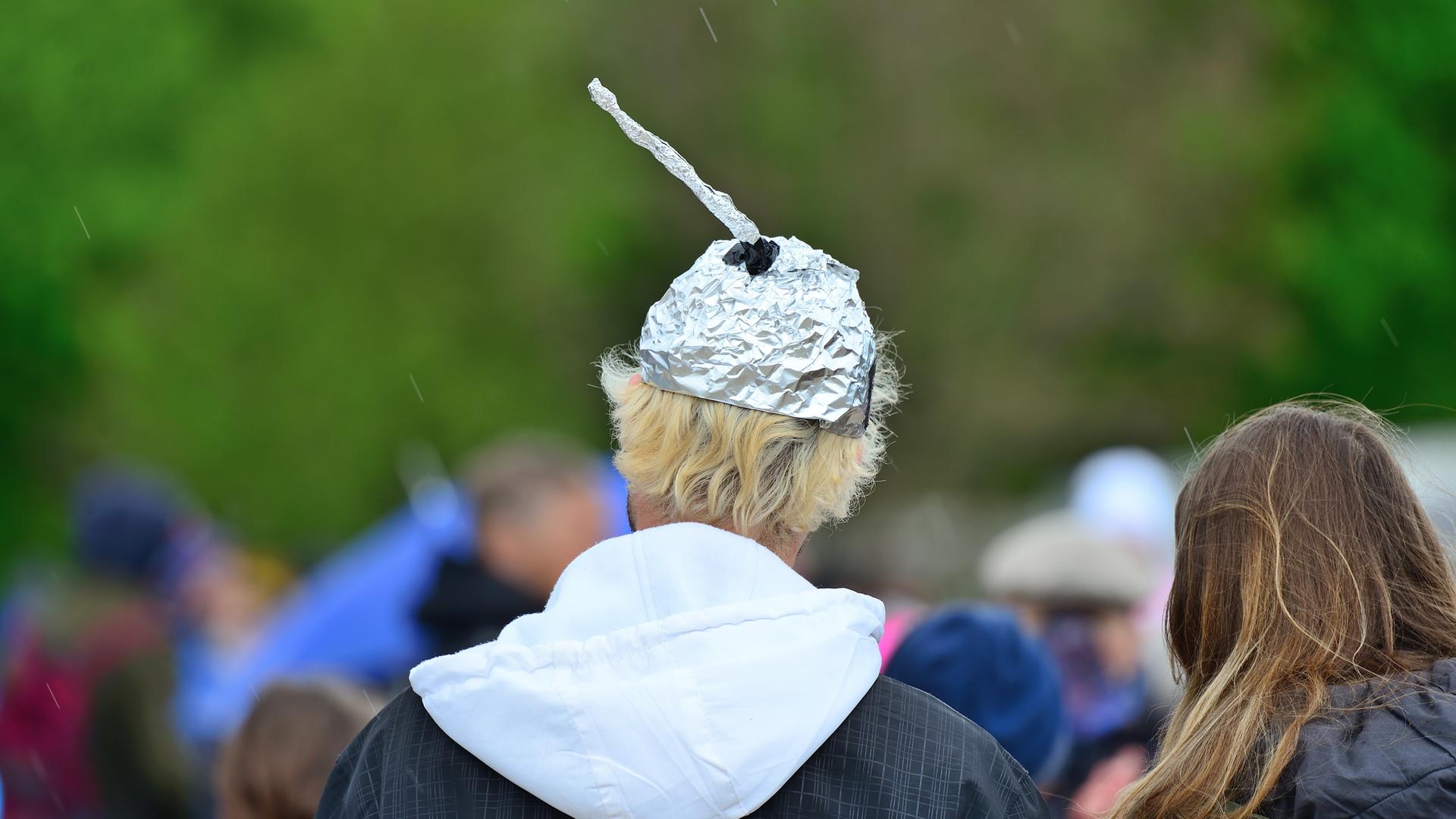 Eine Person, die einen Aluhut trägt, ist von hinten zu sehen.