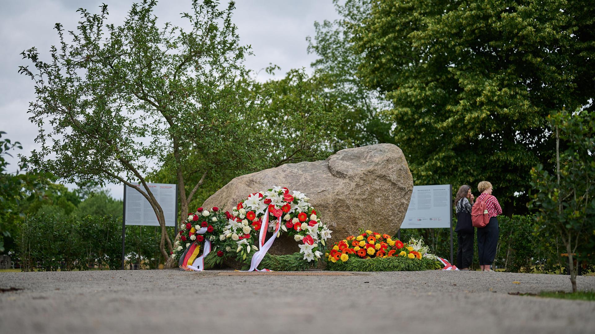 An einem Findling, dem temporären Gedenkort für die Opfer der deutschen Besatzung Polens im Zweiten Weltkrieg im Regierungsviertel in Berlin, liegen Blumenkränze mit deutschen und polnischen Flaggen.  