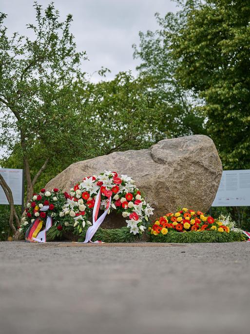 An einem Findling, dem temporären Gedenkort für die Opfer der deutschen Besatzung Polens im Zweiten Weltkrieg im Regierungsviertel in Berlin, liegen Blumenkränze mit deutschen und polnischen Flaggen.  