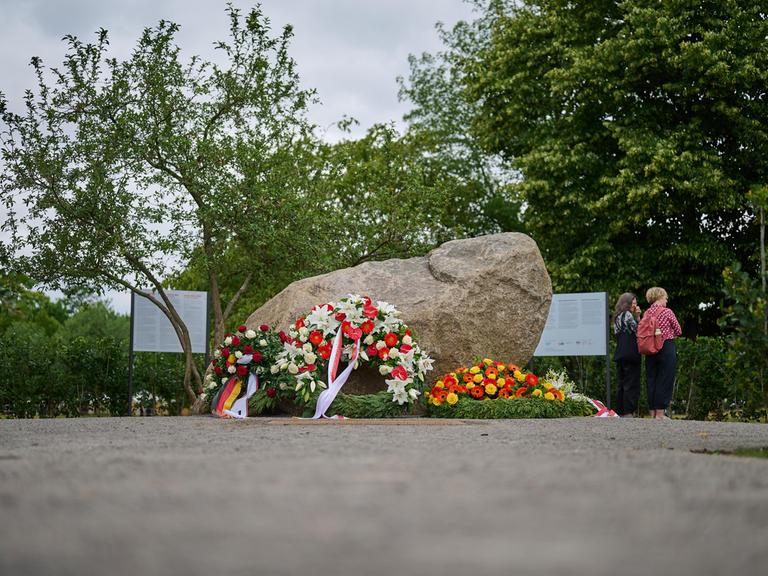 An einem Findling, dem temporären Gedenkort für die Opfer der deutschen Besatzung Polens im Zweiten Weltkrieg im Regierungsviertel in Berlin, liegen Blumenkränze mit deutschen und polnischen Flaggen.  