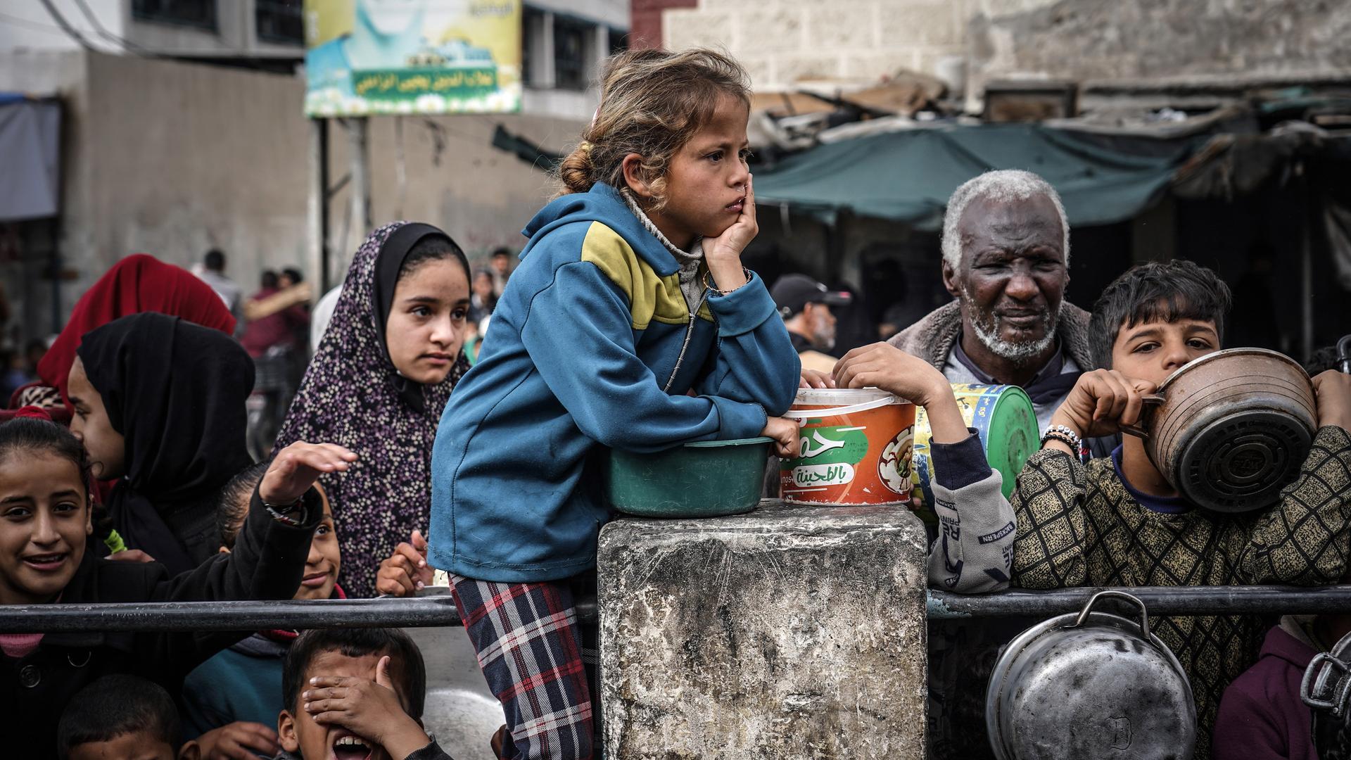 Palästinensische Kinder warten mit Erwachsenen in einer Schlange, um von Freiwilligen zubereitetes Essen zu erhalten